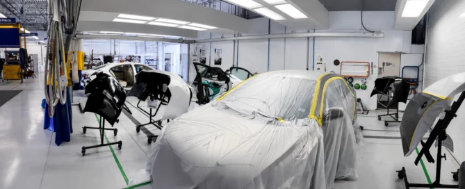Masked vehicle surrounded by exterior panels in a clean paint preparation area.