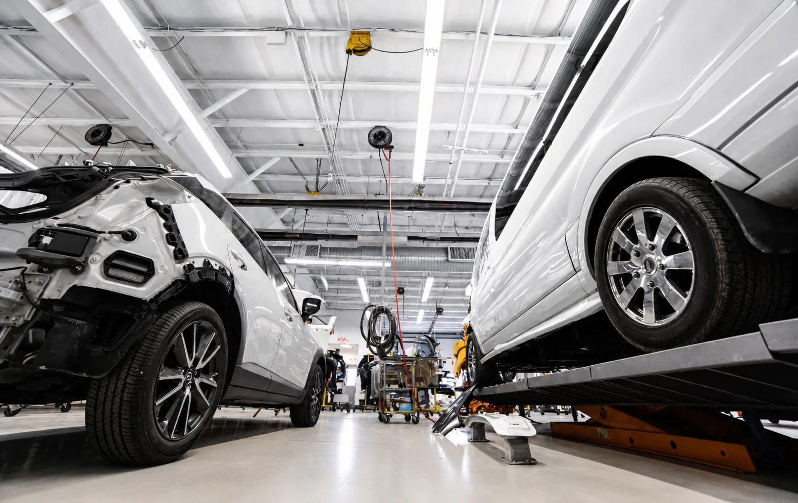 Vehicles In Collision Repair Bay Vehicles staged in a clean collision repair bay with shop equipment nearby.