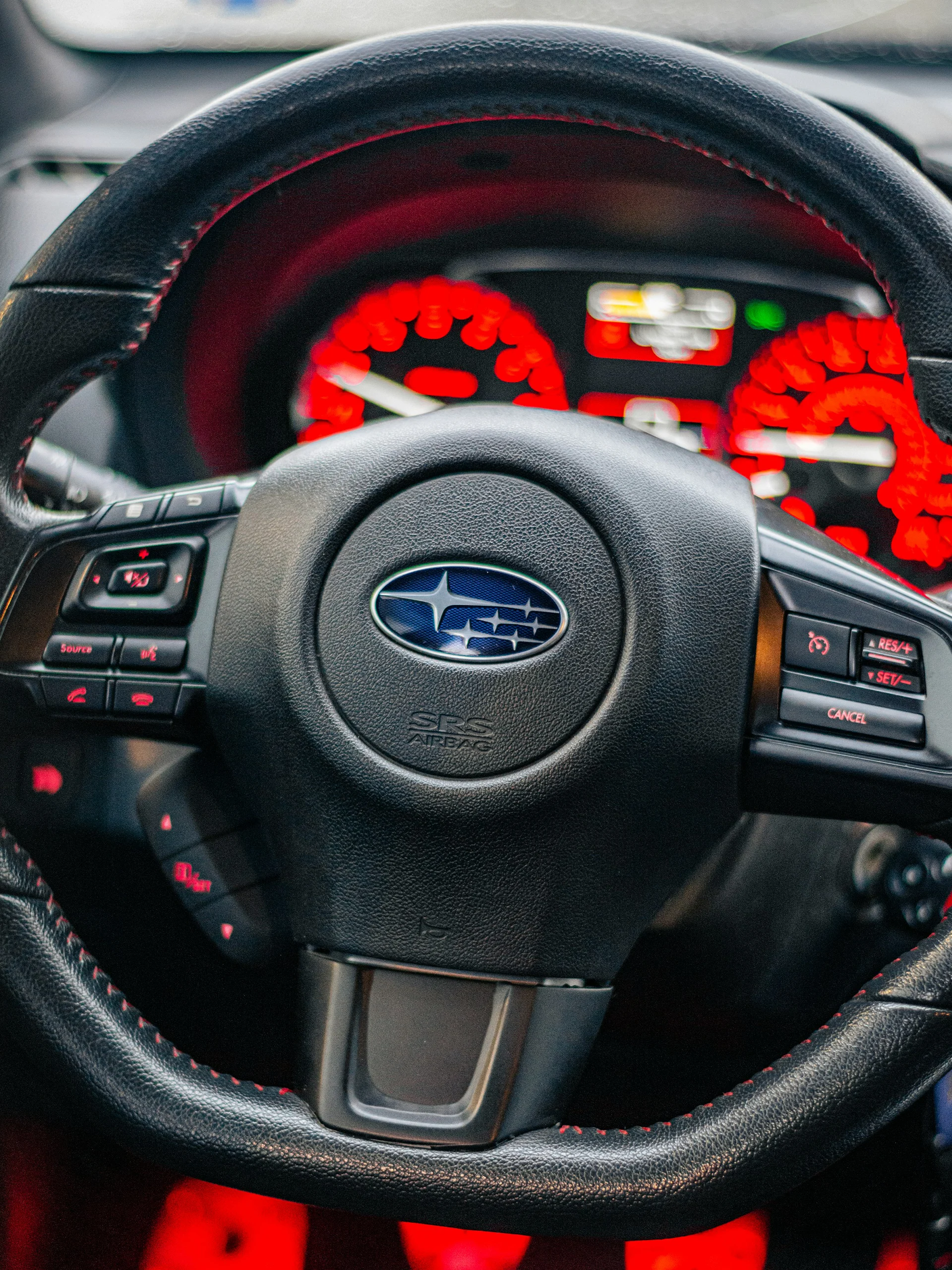 Subaru steering wheel and dashboard controls inside a vehicle interior.